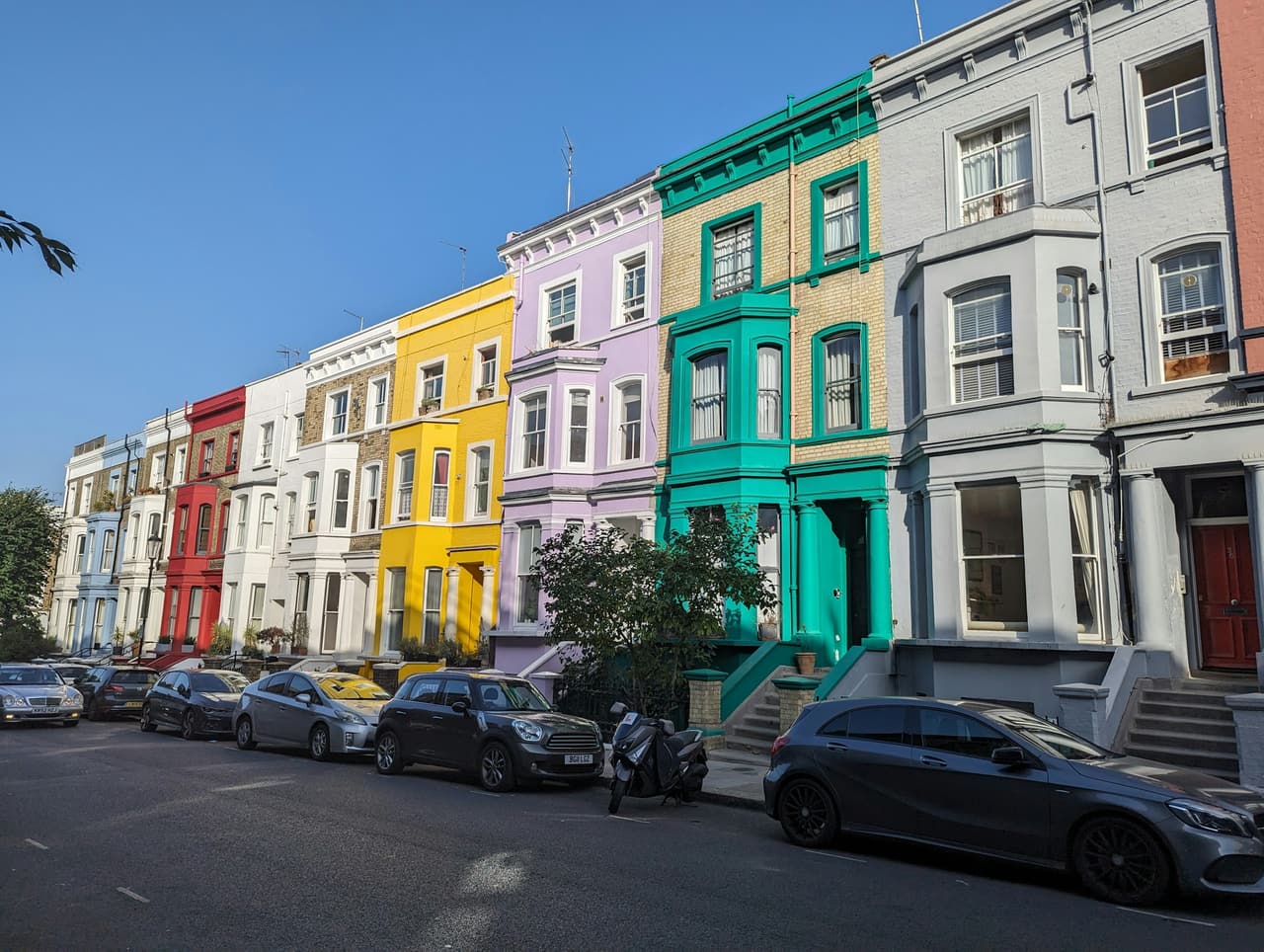 A row of pastel-painted terraced houses on a Notting Hill street